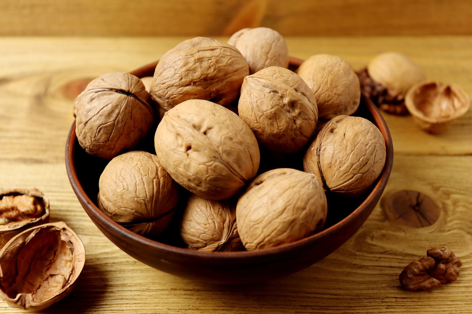 Whole paper-shell walnuts in a rustic bowl